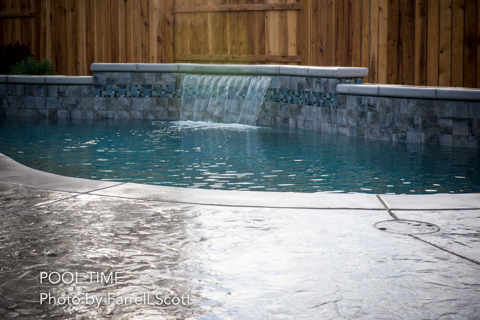 Photo of a mid-sized modern backyard kidney-shaped pool in Sacramento with a water feature and stamped concrete.