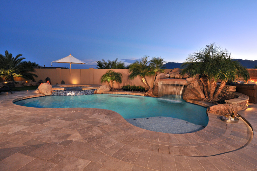 Example of a transitional backyard stone and custom-shaped natural pool fountain design in Phoenix