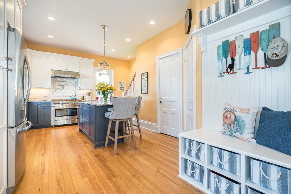 Photo of a large traditional l-shaped eat-in kitchen in New York with a farmhouse sink, shaker cabinets, white cabinets, quartz benchtops, subway tile splashback, stainless steel appliances, light hardwood floors, with island and blue benchtop.