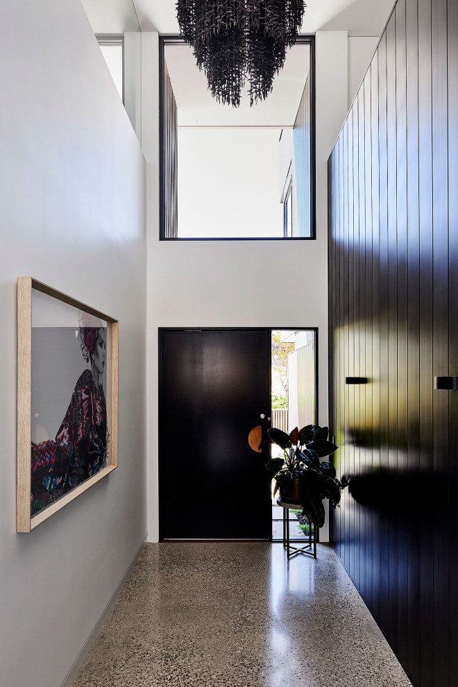 This is an example of a large contemporary foyer in Geelong with black walls, terrazzo floors, a pivot front door, a black front door, grey floor, recessed and decorative wall panelling.