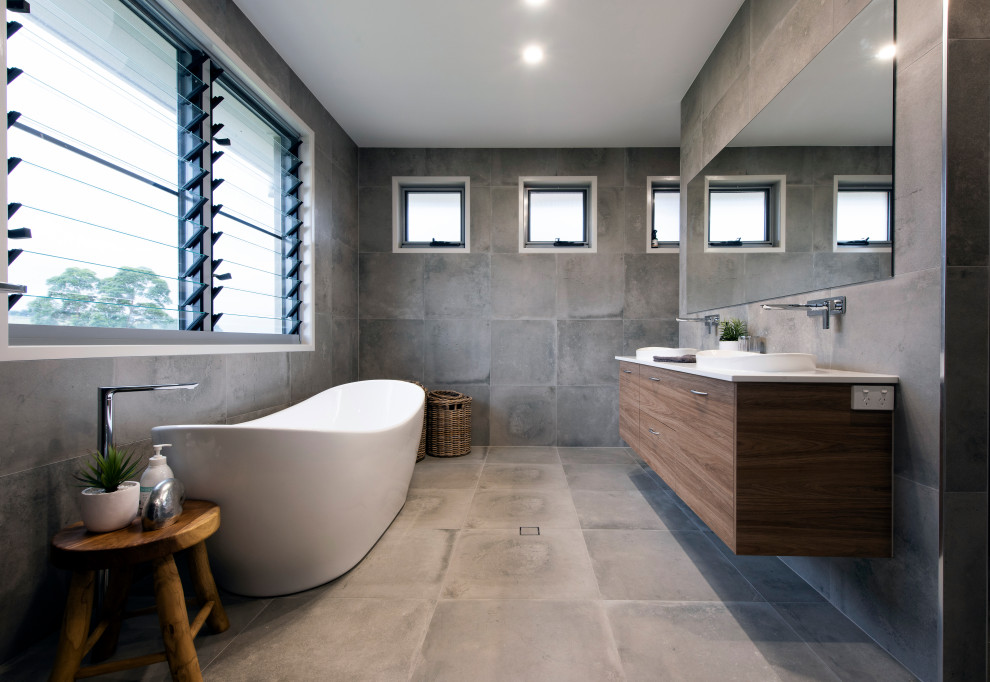 Photo of a contemporary master bathroom in Sunshine Coast with flat-panel cabinets, medium wood cabinets, a freestanding tub, gray tile, grey walls, a drop-in sink, engineered quartz benchtops, grey floor, white benchtops, a double vanity and a floating vanity.