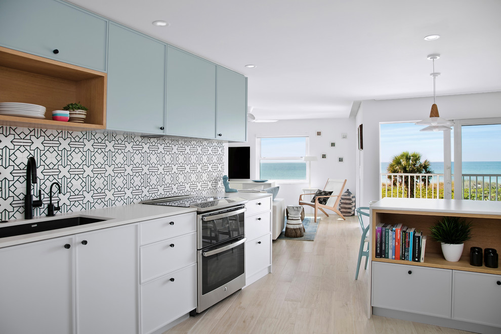 This is an example of a small beach style eat-in kitchen in Tampa with an undermount sink, shaker cabinets, white cabinets, quartzite benchtops, ceramic splashback, stainless steel appliances, ceramic floors, a peninsula and beige floor.