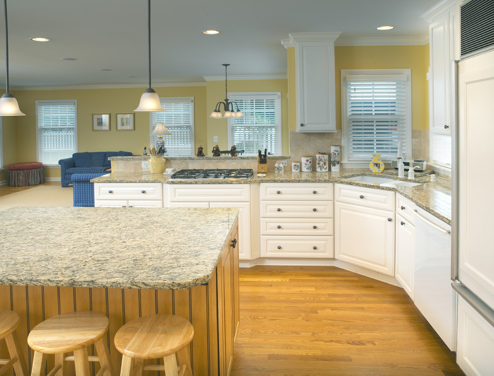 Example of a mid-sized classic light wood floor eat-in kitchen design in Columbus with an undermount sink, white cabinets, granite countertops, beige backsplash, stainless steel appliances, an island and recessed-panel cabinets