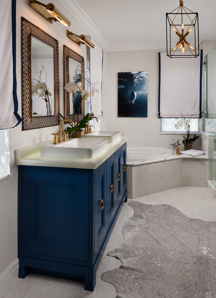 This is an example of a mid-sized transitional master bathroom in Miami with a vessel sink, blue cabinets, a drop-in tub, grey walls, marble floors and recessed-panel cabinets.