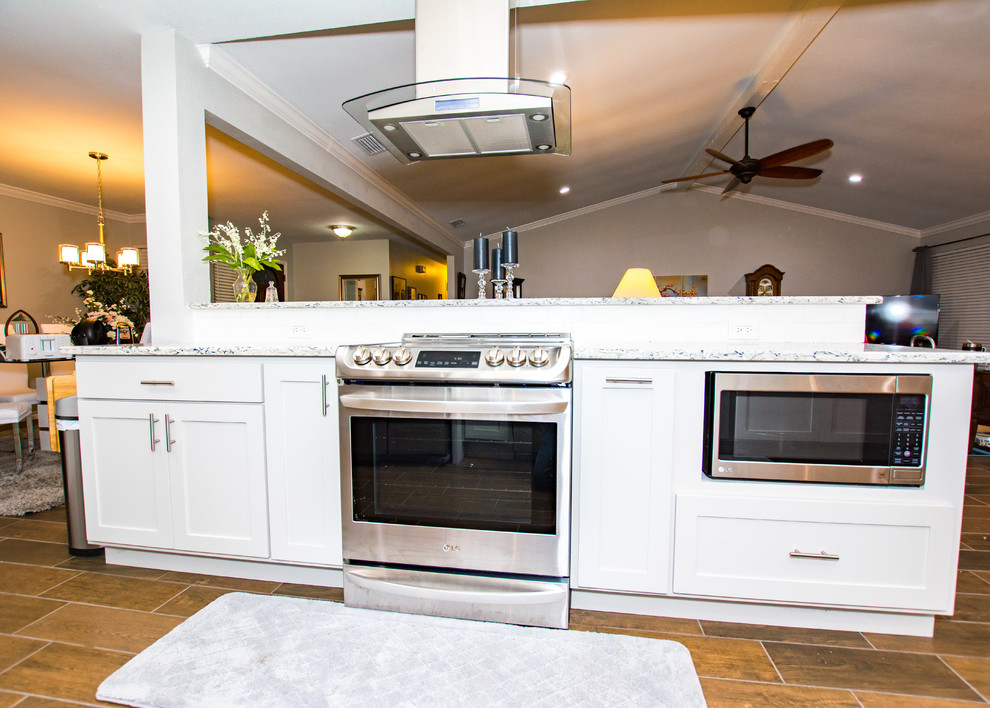 Example of a porcelain tile and brown floor kitchen design in Austin with an undermount sink, shaker cabinets, gray cabinets, quartz countertops, white backsplash, subway tile backsplash, stainless steel appliances and a peninsula