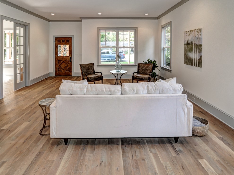Photo of a large transitional open concept living room in Charlotte with white walls, light hardwood floors, no fireplace, no tv and brown floor.