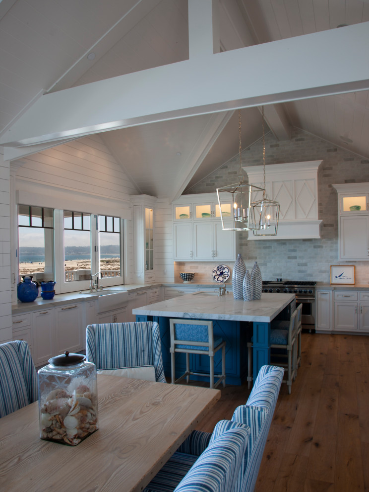 Aménagement d'une grande salle à manger ouverte sur la cuisine bord de mer avec un mur gris, parquet clair, une cheminée standard, un manteau de cheminée en lambris de bois, un sol gris et un plafond voûté.