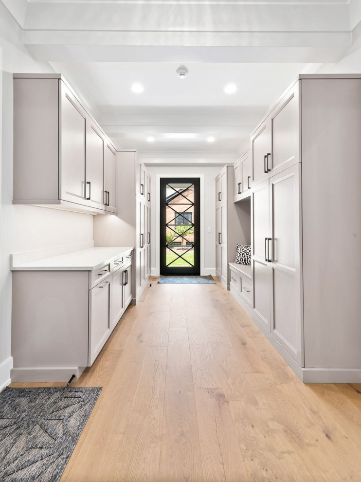 This is an example of a large transitional mudroom in Chicago with grey walls, light hardwood floors, a single front door, a white front door, brown floor and coffered.