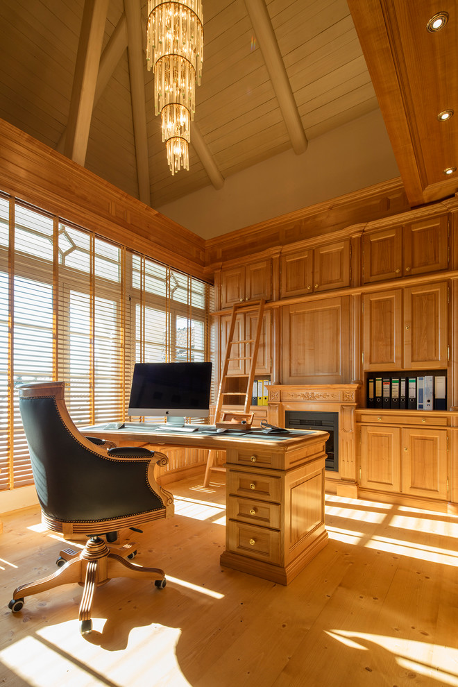 This is an example of a mid-sized traditional study room in Other with light hardwood floors, a freestanding desk and brown walls.