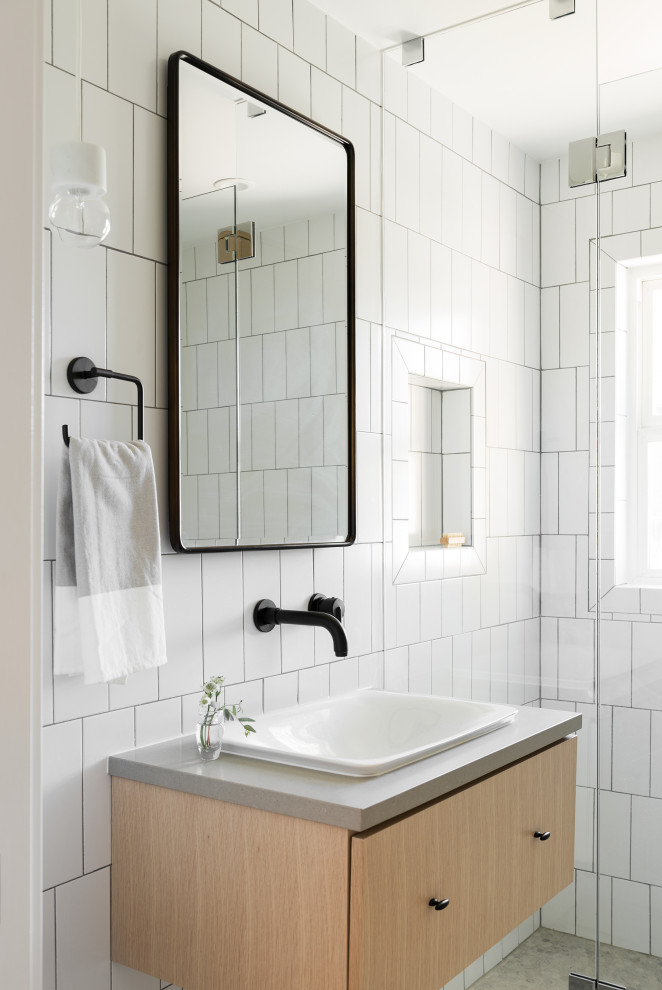 Inredning av ett minimalistiskt litet grå grått badrum, med släta luckor, grå skåp, en dusch i en alkov, vit kakel, keramikplattor, vita väggar, mosaikgolv, ett fristående handfat, bänkskiva i kvarts, grått golv och dusch med gångjärnsdörr