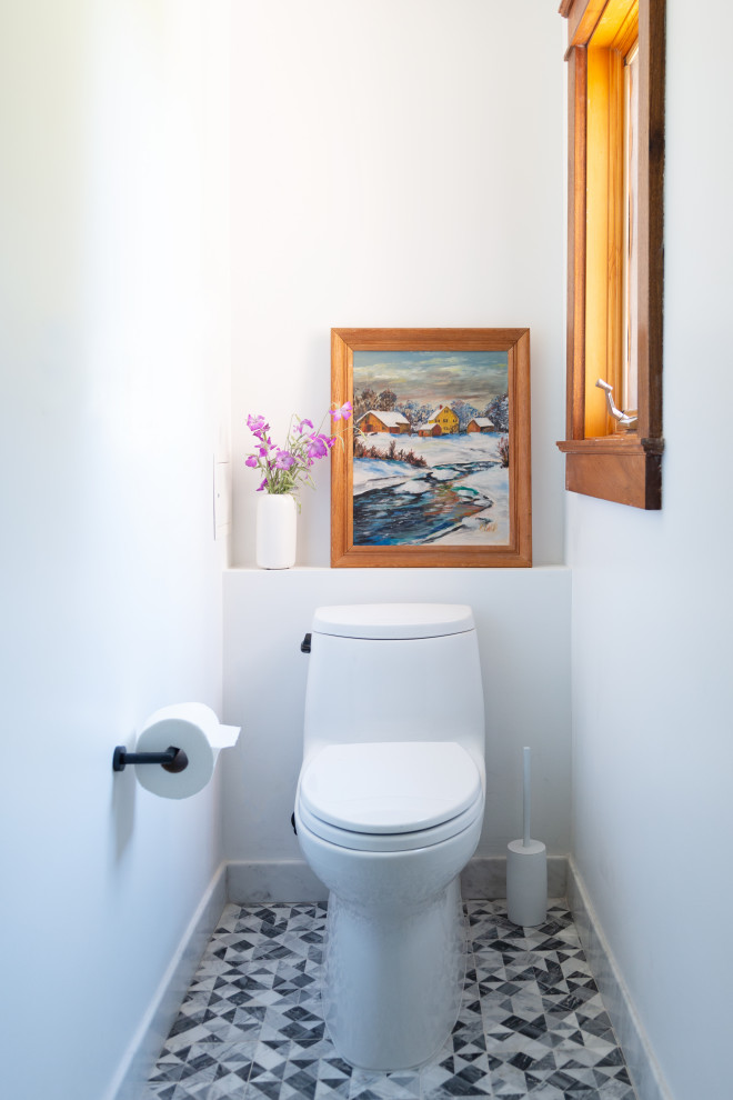 Inredning av ett modernt litet toalett, med en toalettstol med hel cisternkåpa, mosaikgolv och vita väggar