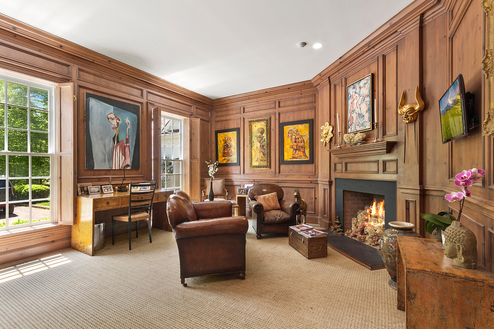 This is an example of a large traditional study room in New York with carpet, a corner fireplace, a freestanding desk, brown walls, a metal fireplace surround and beige floor.