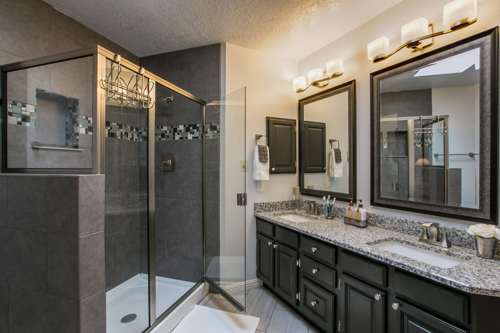 Inspiration for a mid-sized transitional master bathroom in Albuquerque with raised-panel cabinets, black cabinets, an alcove tub, a double shower, a two-piece toilet, gray tile, porcelain tile, grey walls, porcelain floors, an undermount sink and granite benchtops.