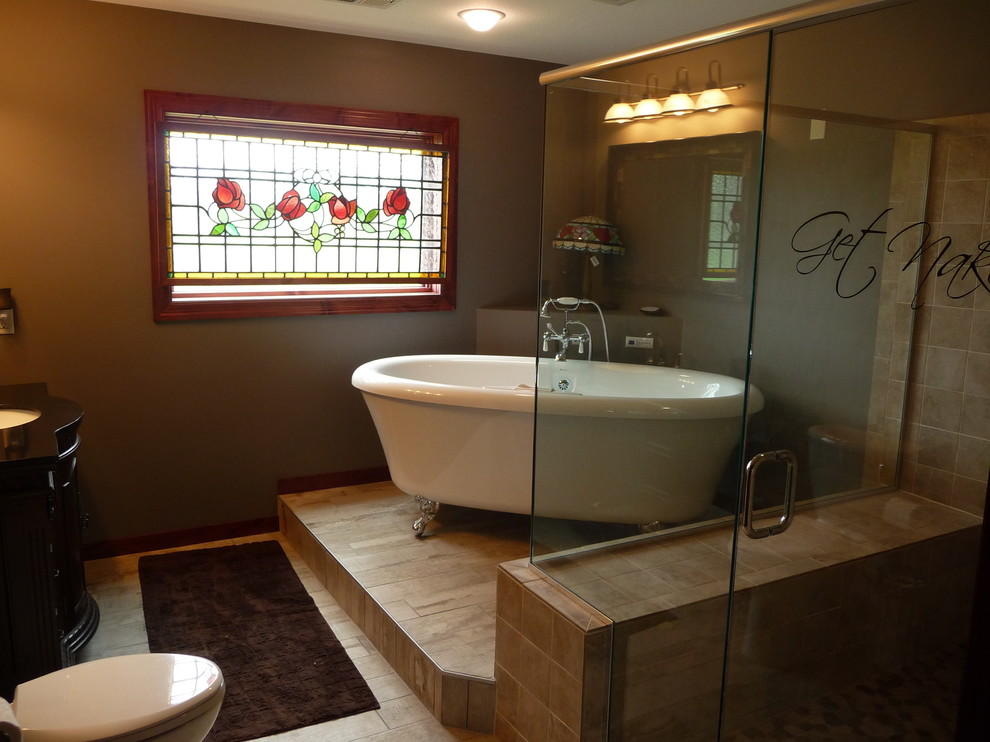 This is an example of a large mediterranean master bathroom in Minneapolis with recessed-panel cabinets, black cabinets, a claw-foot tub, a corner shower, a one-piece toilet, beige tile, ceramic tile, beige walls, ceramic floors, an undermount sink, granite benchtops, beige floor and a hinged shower door.