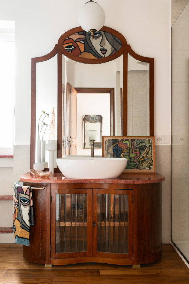 Cette image montre une salle de bain principale méditerranéenne en bois foncé de taille moyenne avec un placard à porte vitrée, un carrelage beige, des carreaux en terre cuite, un mur blanc, parquet foncé, une vasque, un plan de toilette en marbre, un sol marron, un plan de toilette rouge, meuble simple vasque et meuble-lavabo sur pied.