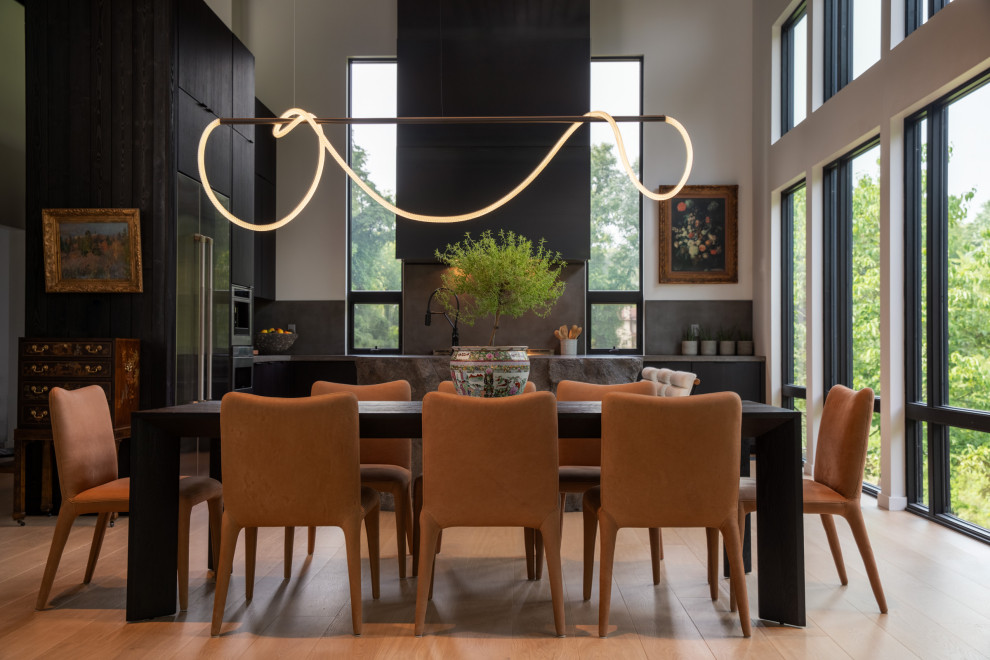 Inspiration for a large contemporary open plan dining in Other with grey walls, light hardwood floors, a standard fireplace, a concrete fireplace surround, brown floor, vaulted and wood walls.
