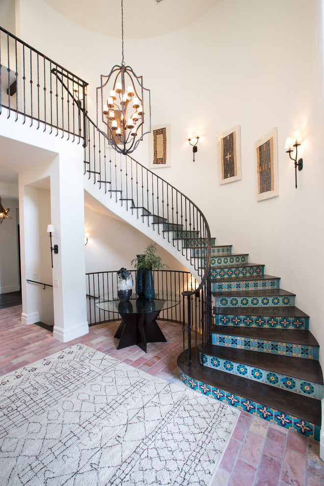 Mediterranean wood curved staircase in Orange County with tile risers and metal railing.
