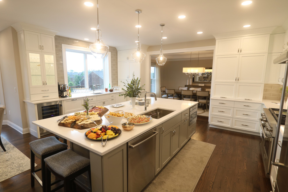 Eat-in kitchen - huge transitional u-shaped dark wood floor and brown floor eat-in kitchen idea in Cincinnati with an undermount sink, recessed-panel cabinets, white cabinets, quartz countertops, beige backsplash, subway tile backsplash, stainless steel appliances, an island and white countertops