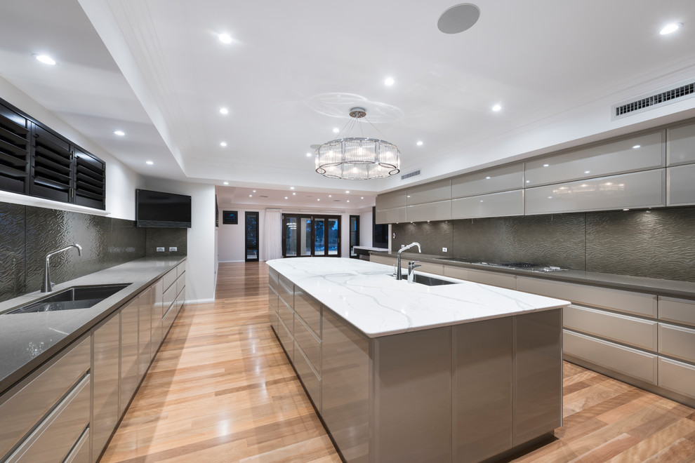This is an example of an expansive contemporary galley eat-in kitchen in Perth with an undermount sink, grey cabinets, quartz benchtops, brown splashback, glass sheet splashback, stainless steel appliances, medium hardwood floors, with island and brown floor.