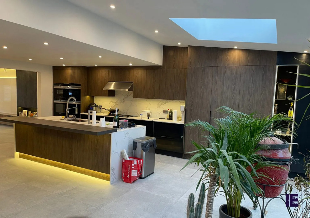 Eat-in kitchen - large contemporary single-wall eat-in kitchen idea in London with a single-bowl sink, flat-panel cabinets, medium tone wood cabinets, granite countertops, white backsplash and a peninsula