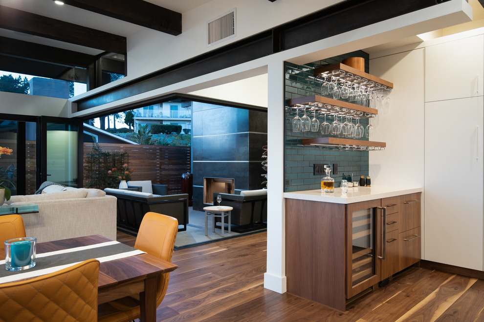 Mid-sized single-wall home bar in San Diego with no sink, flat-panel cabinets, medium wood cabinets, quartz benchtops, green splashback, ceramic splashback, medium hardwood floors and beige benchtop.