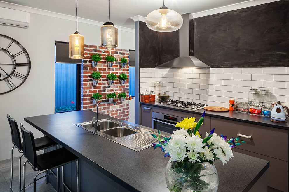 This is an example of a mid-sized kitchen in Perth with a double-bowl sink, brown cabinets, solid surface benchtops, white splashback, ceramic splashback, stainless steel appliances, ceramic floors and with island.