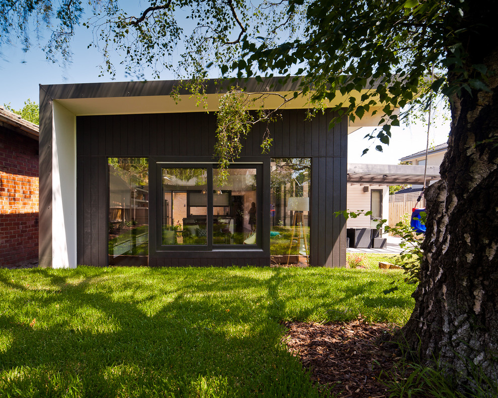 Photo of a contemporary one-storey black exterior in Melbourne with mixed siding and a flat roof.