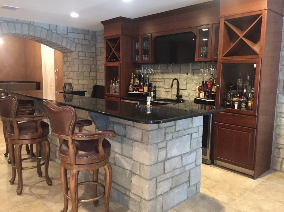 Design ideas for a mid-sized transitional seated home bar in Philadelphia with an undermount sink, recessed-panel cabinets, medium wood cabinets, granite benchtops, grey splashback, stone tile splashback and travertine floors.