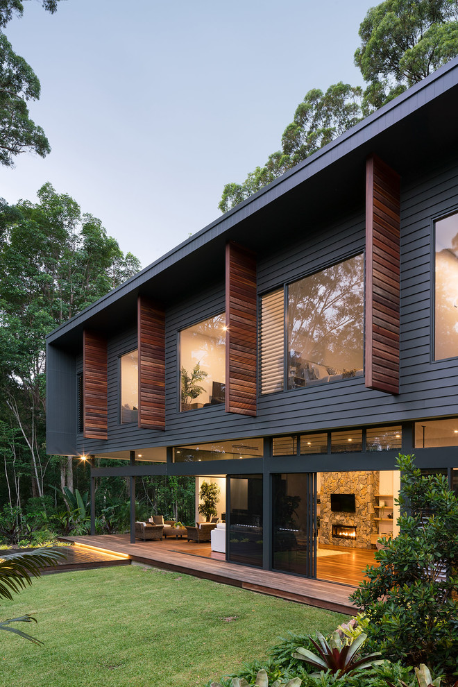 This is an example of a mid-sized contemporary two-storey black house exterior in Sunshine Coast with concrete fiberboard siding, a flat roof and a metal roof.
