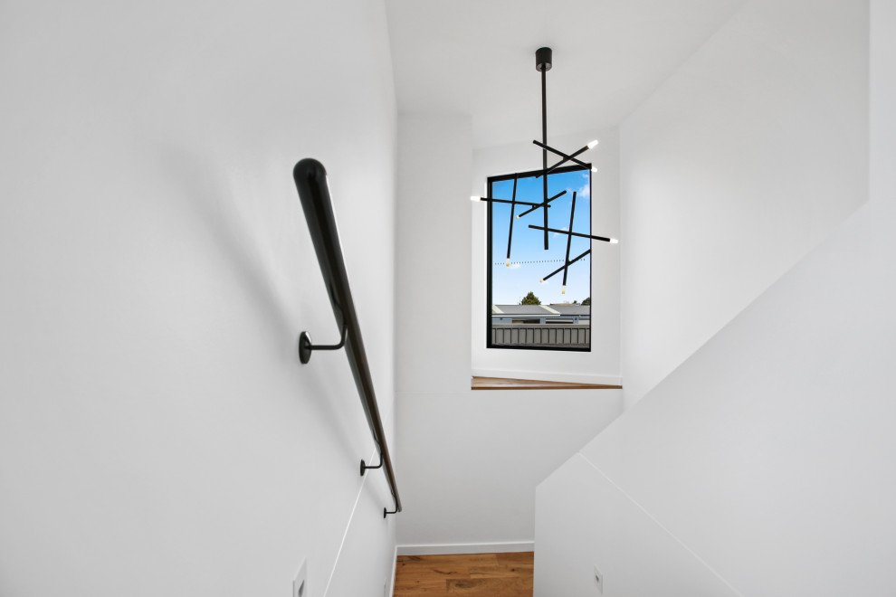 Large modern wood u-shaped staircase with wood risers and metal railing.