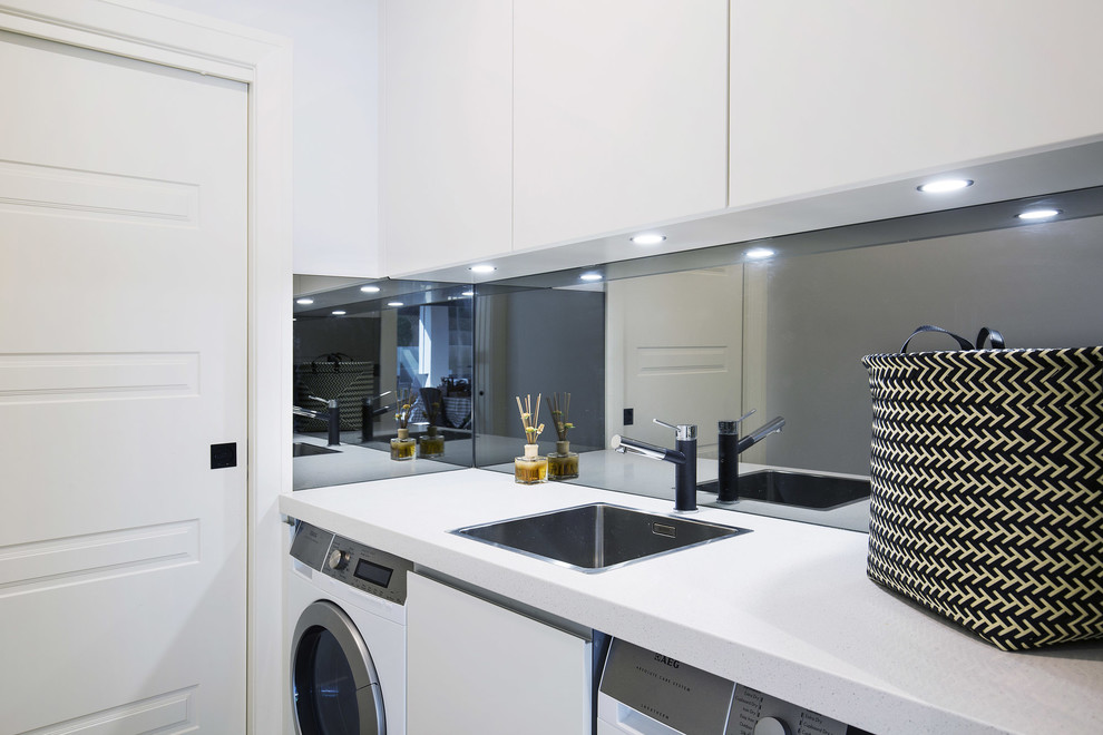 Inspiration for a small modern single-wall dedicated laundry room in Sydney with a single-bowl sink, flat-panel cabinets, white cabinets, quartz benchtops, white walls, limestone floors, a side-by-side washer and dryer and beige floor.