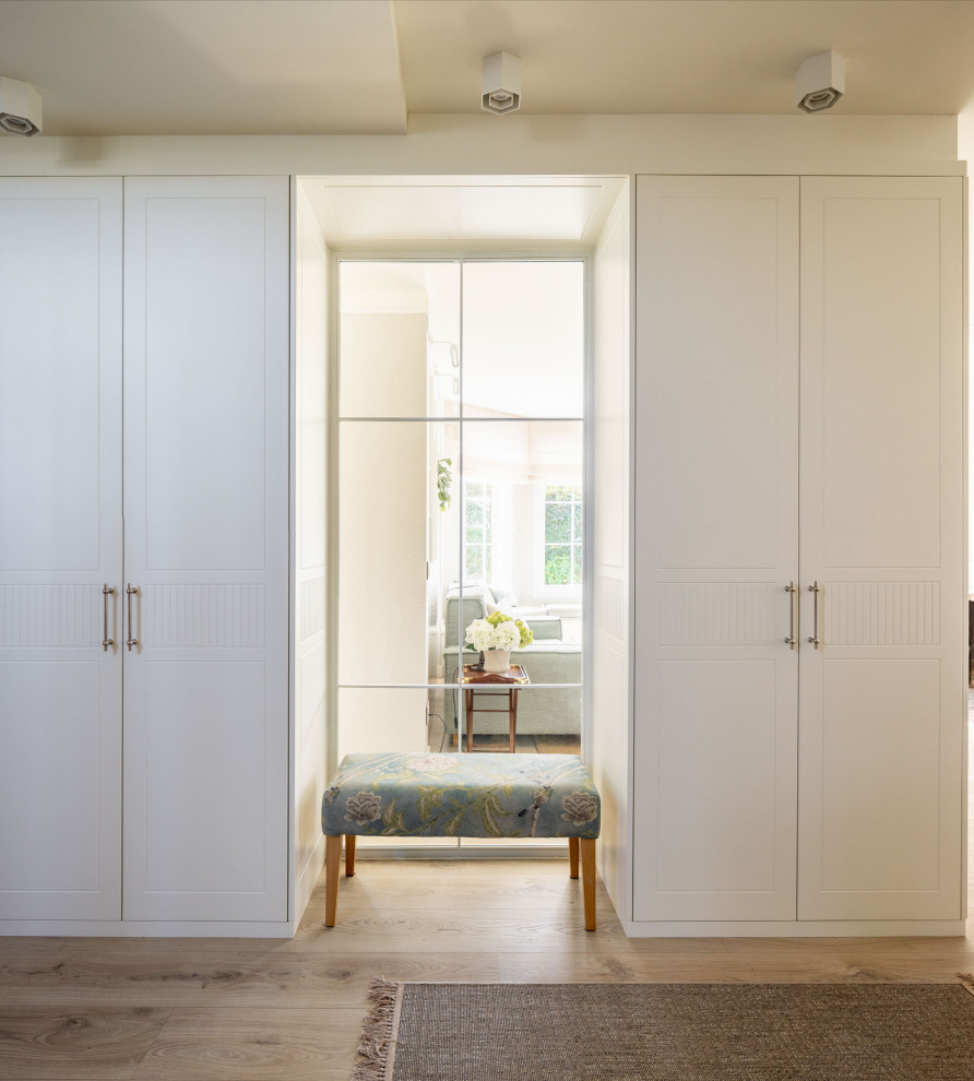 Imagen de vestidor unisex clásico renovado grande con armarios con paneles con relieve, puertas de armario blancas y suelo laminado