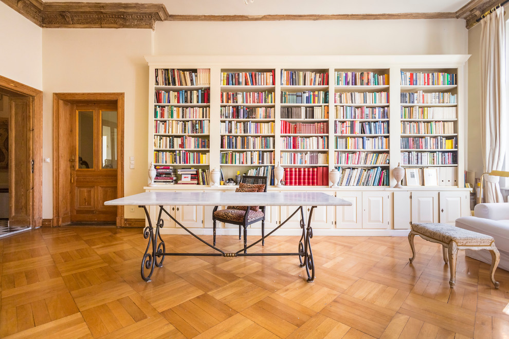 Large eclectic study room in Berlin with white walls, medium hardwood floors and a freestanding desk.