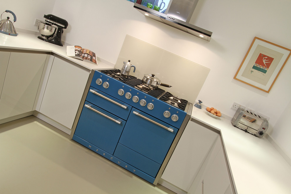 This is an example of a mid-sized modern u-shaped eat-in kitchen in Hampshire with a single-bowl sink, flat-panel cabinets, white cabinets, quartz benchtops, beige splashback, glass sheet splashback, coloured appliances, linoleum floors and a peninsula.