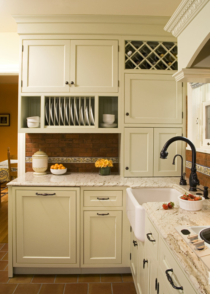 This is an example of a traditional kitchen in Seattle with a farmhouse sink, beaded inset cabinets, green cabinets, granite benchtops, red splashback and terra-cotta splashback.