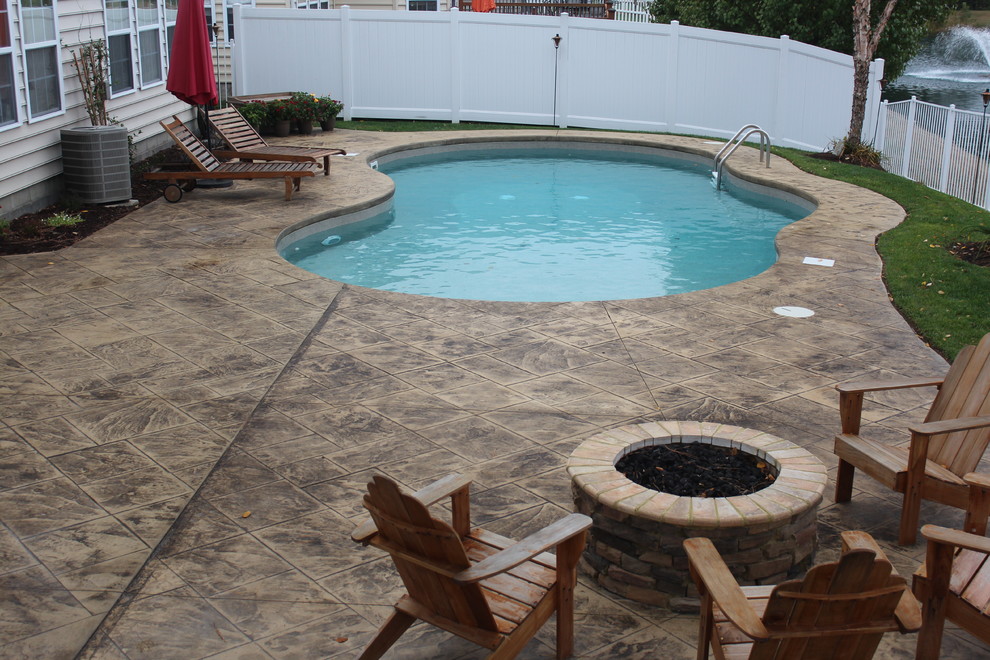 Pool - mid-sized tropical backyard stamped concrete and custom-shaped pool idea