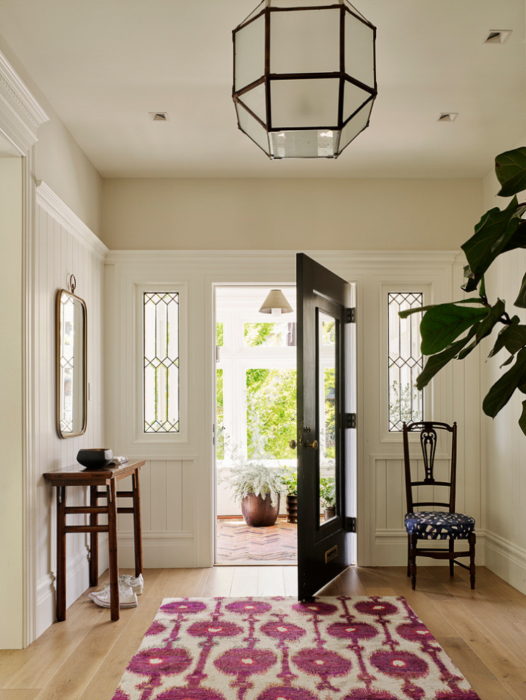 This is an example of a mid-sized beach style foyer in San Francisco with light hardwood floors, a single front door, a black front door, beige walls and beige floor.