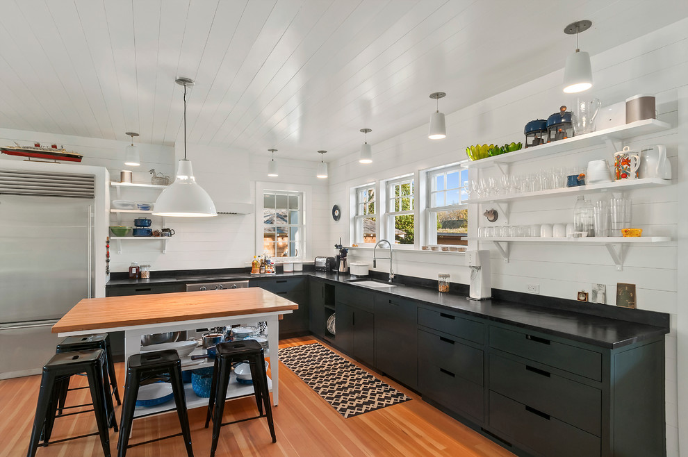 Photo of a large beach style l-shaped kitchen in New York with an undermount sink, flat-panel cabinets, stainless steel appliances and with island.