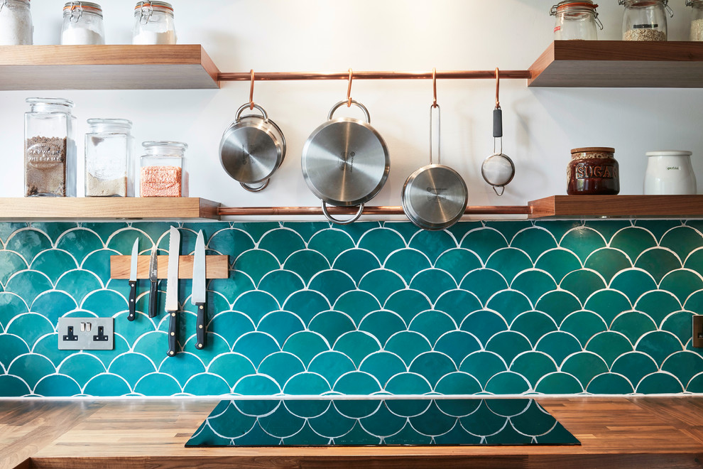 Inspiration for a small eclectic u-shaped separate kitchen in London with a farmhouse sink, flat-panel cabinets, blue cabinets, wood benchtops, blue splashback, cement tile splashback, stainless steel appliances, dark hardwood floors, no island and brown floor.