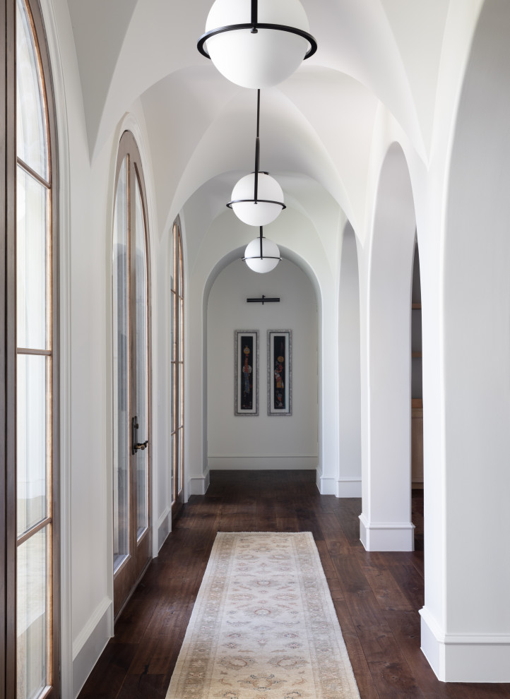 На фото: коридор в средиземноморском стиле с белыми стенами, темным паркетным полом, коричневым полом и сводчатым потолком