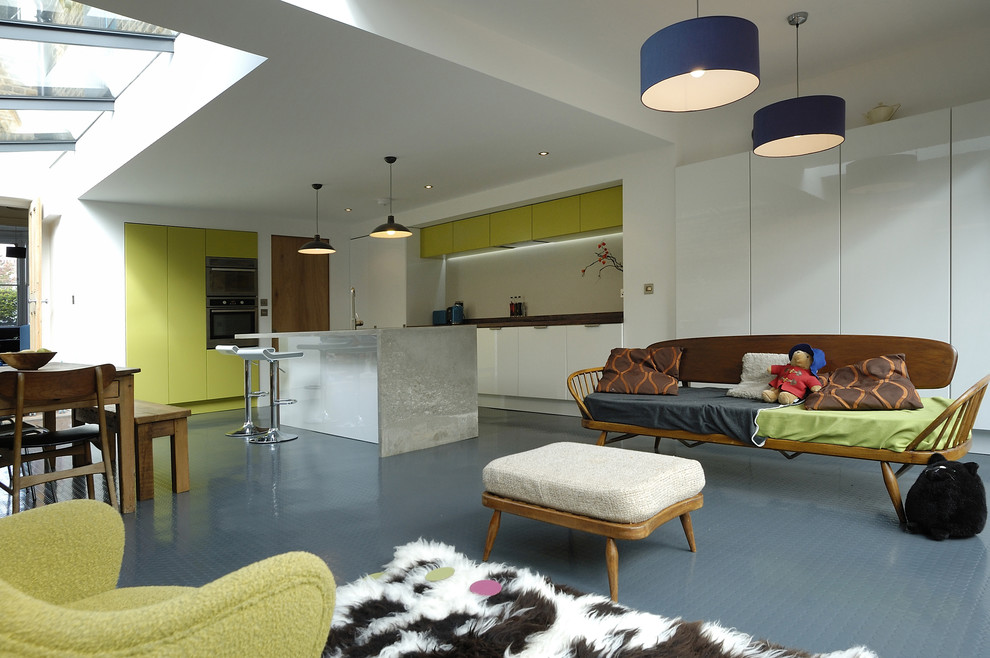 Modern open plan kitchen in London with concrete benchtops, green cabinets and flat-panel cabinets.