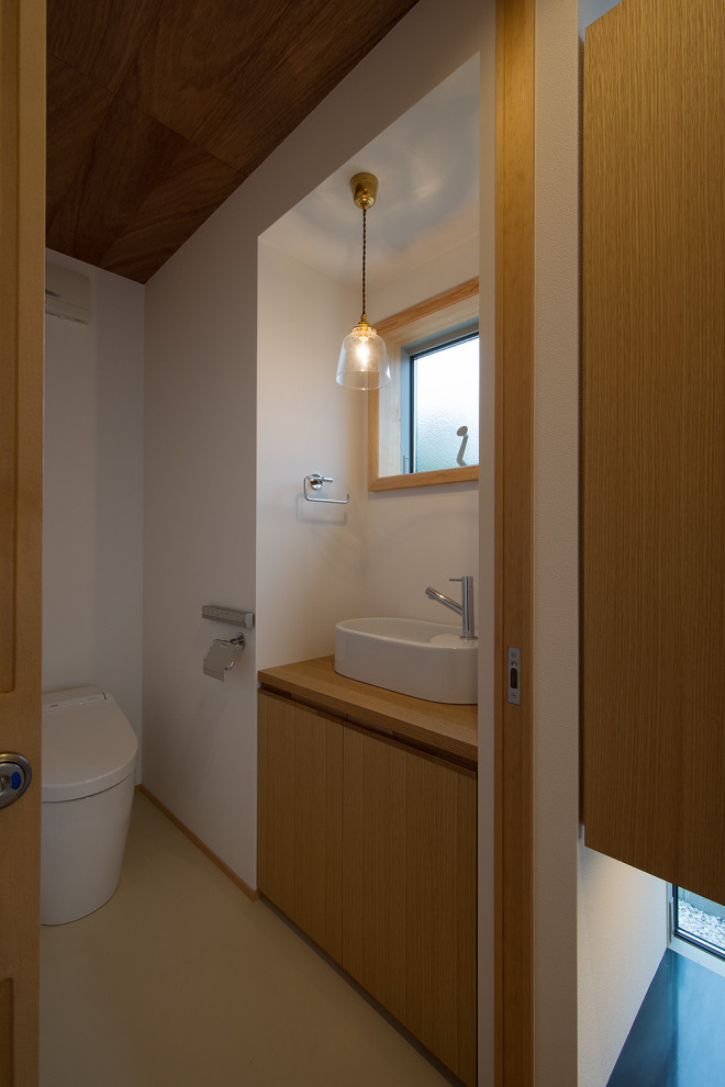 This is an example of a mid-sized scandinavian powder room in Other with flat-panel cabinets, medium wood cabinets, a one-piece toilet, white walls, vinyl floors, a vessel sink, beige floor, brown benchtops, a built-in vanity, wood and wallpaper.