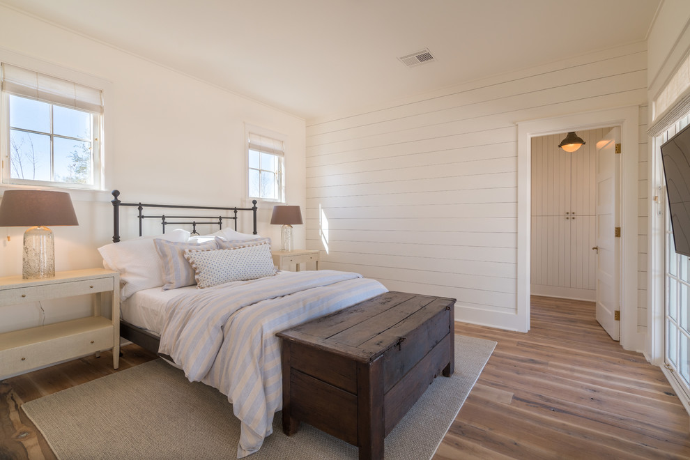 Inspiration for a country bedroom in Austin with medium hardwood floors, white walls and brown floor.