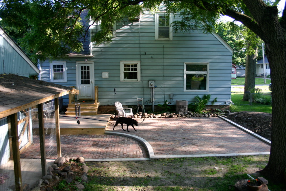 Mid-sized transitional backyard brick patio photo with no cover