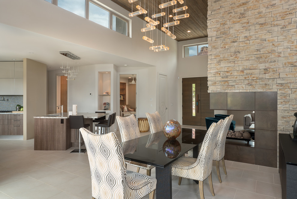 This is an example of a large contemporary kitchen/dining combo in Phoenix with a two-sided fireplace, white walls, porcelain floors, beige floor and a stone fireplace surround.