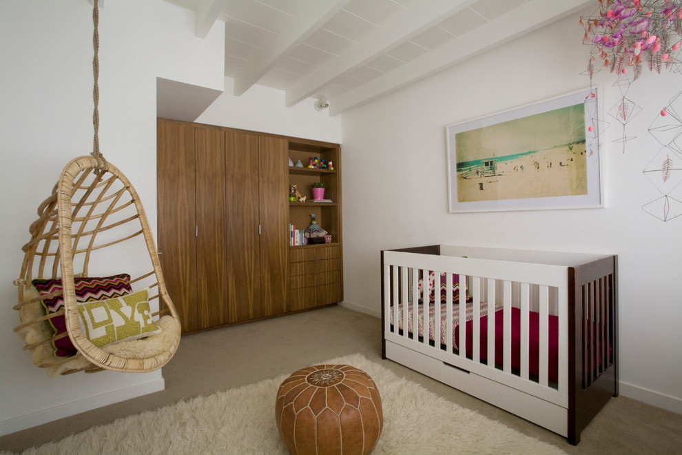 This is an example of a mid-sized modern nursery for girls in San Diego with white walls and carpet.