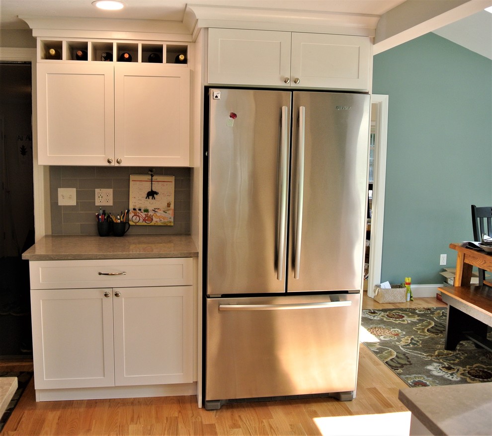 Example of a transitional light wood floor kitchen design in Boston with an undermount sink, shaker cabinets, white cabinets, quartz countertops, gray backsplash, subway tile backsplash, stainless steel appliances, an island and gray countertops