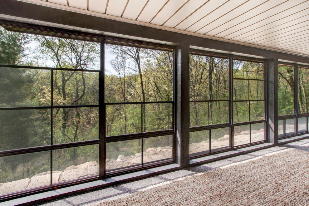 This is an example of an expansive country sunroom in Milwaukee with concrete floors, a standard ceiling and grey floor.