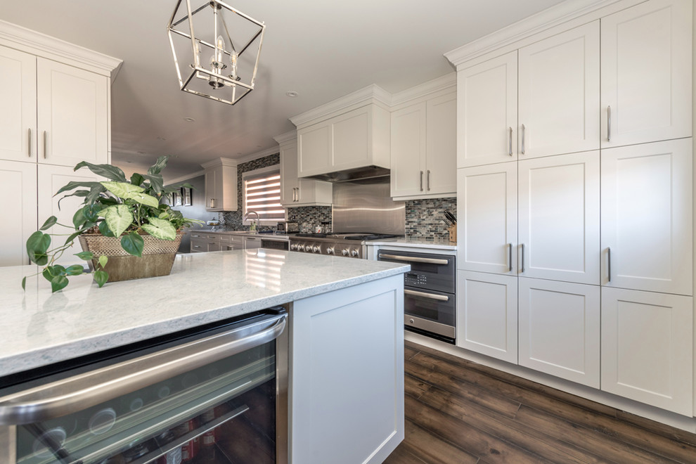 Eat-in kitchen - large transitional galley dark wood floor and brown floor eat-in kitchen idea with an undermount sink, shaker cabinets, white cabinets, quartz countertops, multicolored backsplash, mosaic tile backsplash, stainless steel appliances, an island and multicolored countertops