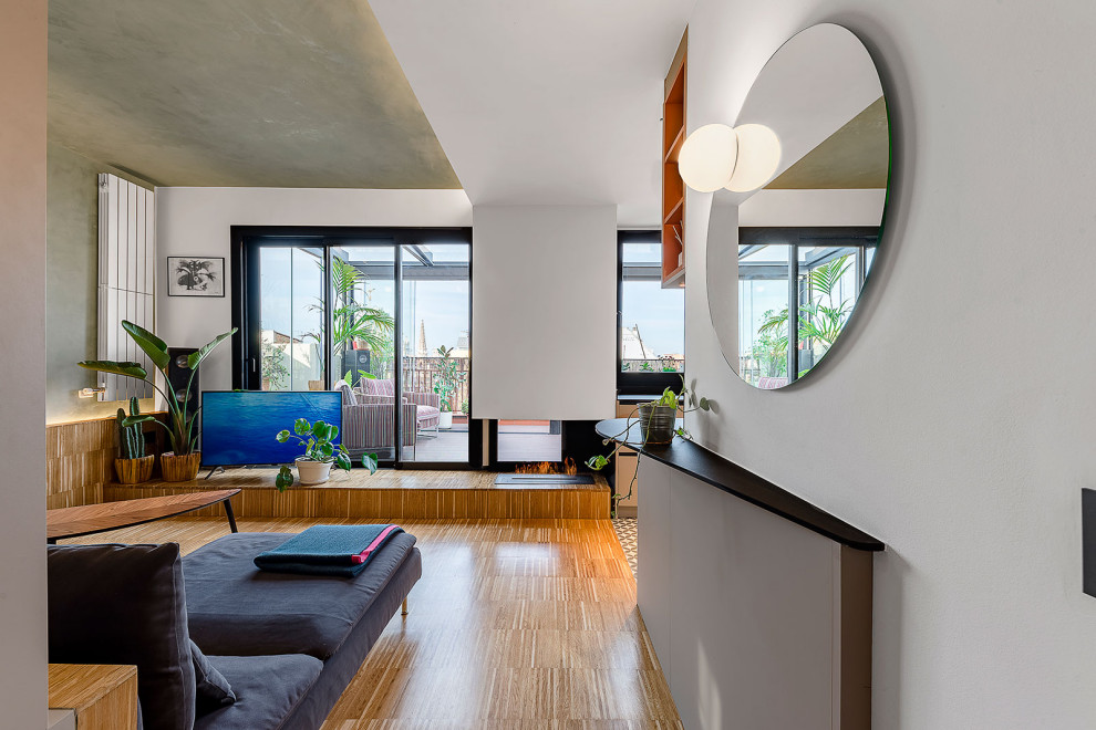 Foto de sala de estar abierta contemporánea pequeña con suelo de madera en tonos medios, chimenea de esquina, marco de chimenea de metal y suelo marrón